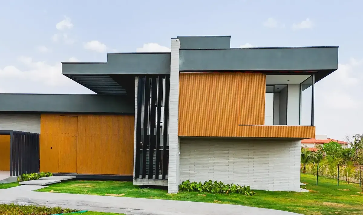 Fachada lateral da Casa Aroeiras com volume em madeira e concreto, obra entregue por construtora confiável da região de Goiânia