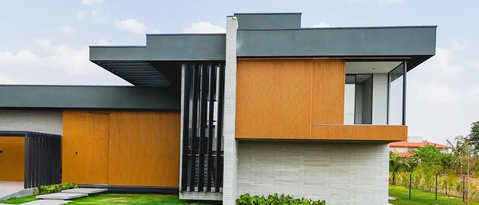 Fachada lateral da Casa Aroeiras com volume em madeira e concreto, obra entregue por construtora confiável da região de Goiânia