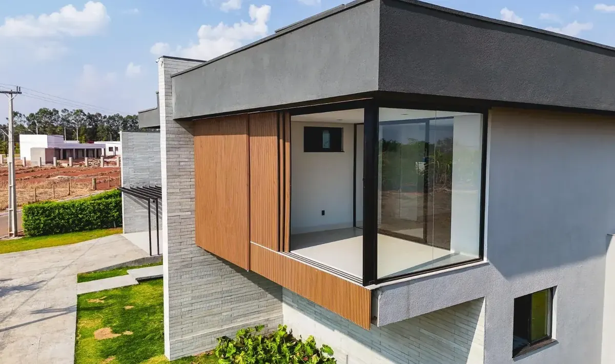 Fachada da Casa Jacarandá com volume em balanço revestido em madeira, casa construída seguindo as regras de obra de condomínio fechado na região de Goiânia
