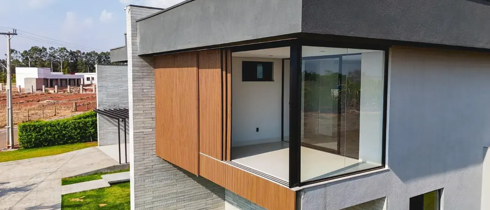 Fachada da Casa Jacarandá com volume em balanço revestido em madeira, casa construída seguindo as regras de obra de condomínio fechado na região de Goiânia