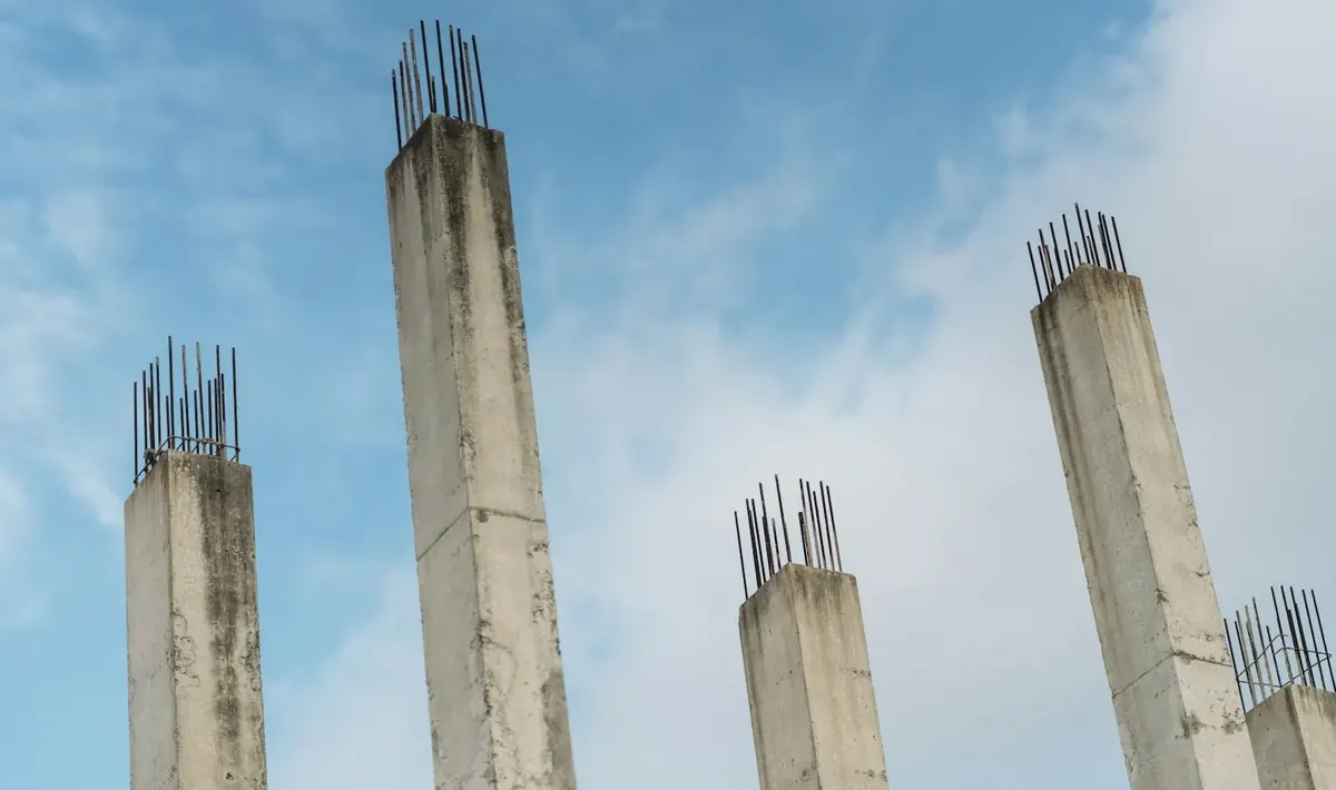 Pilares de concreto manchados pelo tempo, com barras de aço aparentes no topo, imagem que ilustra a recuperação estrutural em Goiânia