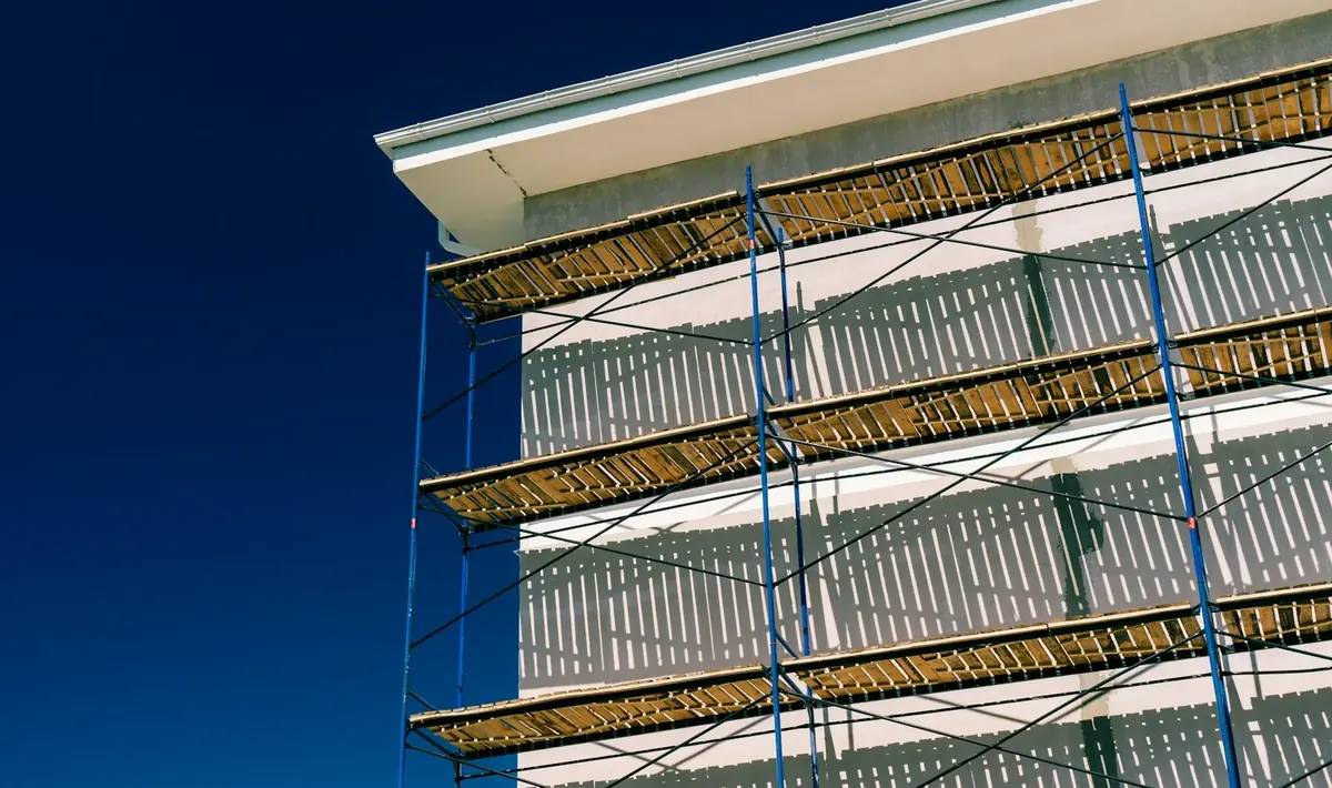 Andaime metálico azul com pranchas de madeira montado na parede externa de um prédio, estrutura usada na reforma predial em Goiânia