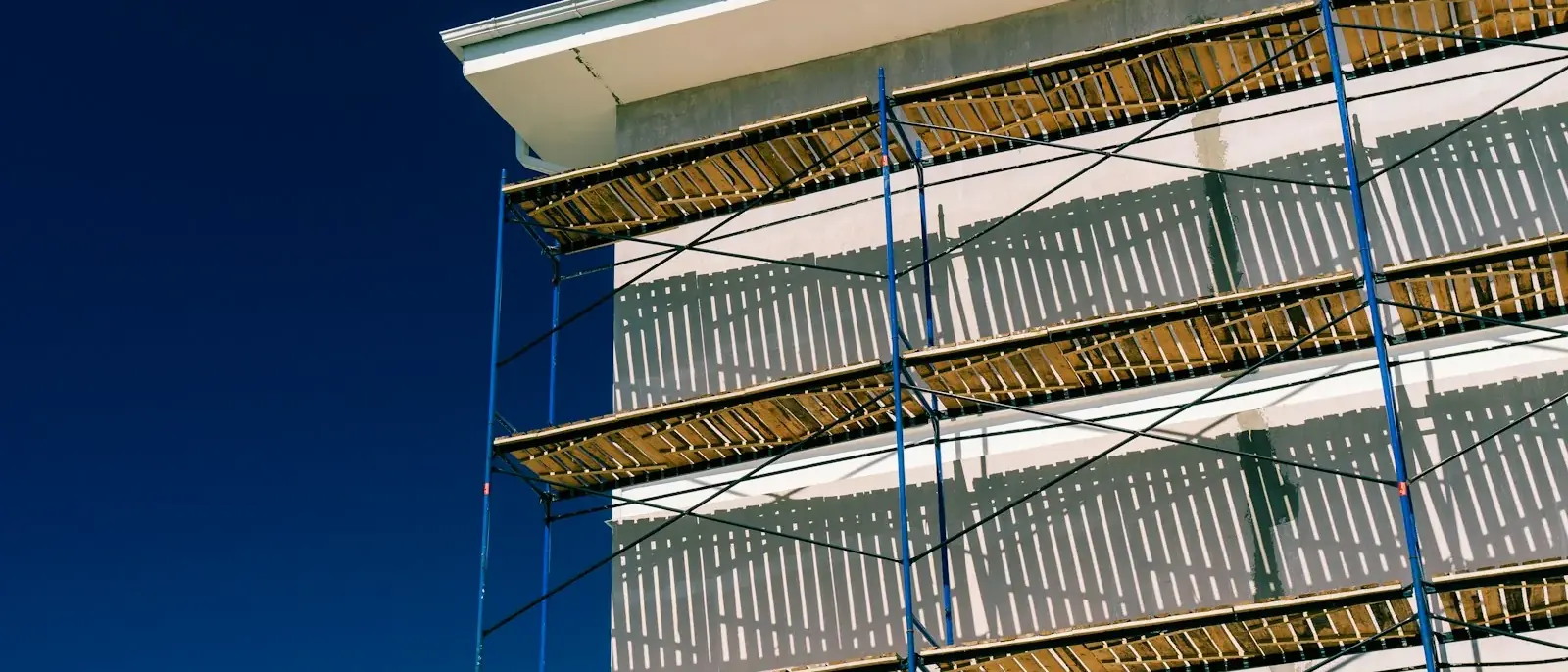 Andaime metálico azul com pranchas de madeira montado na parede externa de um prédio, estrutura usada na reforma predial em Goiânia